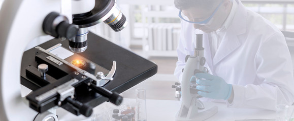 Laboratory concept; close up of microscope with a blurred picture of the scientist is researching in laboratory