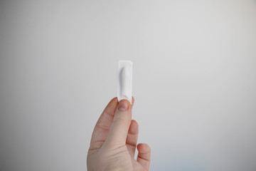 Vaginal or rectal candle in hands on a light background. The drug is in the form of suppositories....