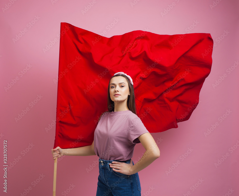 Wall mural activist and revolutionary, young woman with a red flag on a pink background.