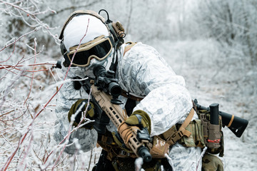 Closeup military man in white camouflage uniform with machinegun. Soldier sneaking in the winter forest with machinegun. Front view.