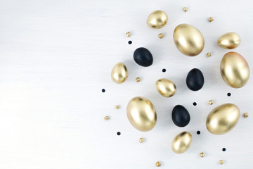 Minimal gold eggs easter concept. Stylish easter golden and black eggs on white wooden background. Flat lay trendy easter. Happy easter card with copy space for text