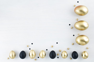 Minimal gold eggs easter concept. Stylish easter golden and black eggs on white wooden background. Flat lay trendy easter. Happy easter card with copy space for text