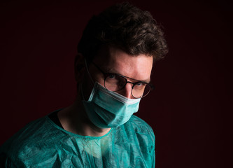 Doctor in protective medical mask. Nurse in glasses prepare for surgery. Medic disposable medical clothing against for a pandemic and flu season.