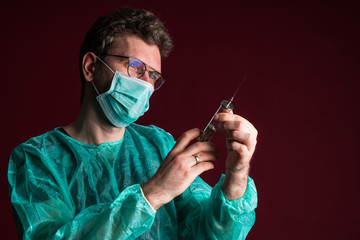 Doctor in medical mask make protective injection. Nurse in glasses prepare syringe. Medic preparing vaccination against for a pandemic and flu season. Dentist in disposable medical clothing.