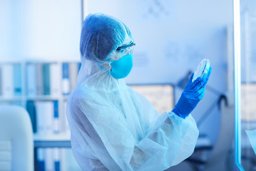 Horizontal side view shot of unrecognizable medical laboratory scientist holding petri dish with...