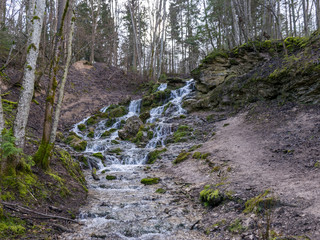 A stream of water flowing over rocks and creating a waterfall effect.