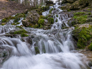 Fototapeta na wymiar A stream of water flowing over rocks and creating a waterfall effect.