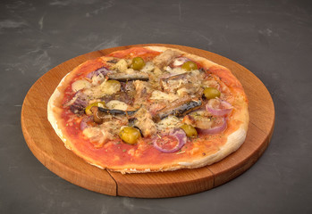 Pizza with sardines, tomatoes and olives on a thin dough.On black background