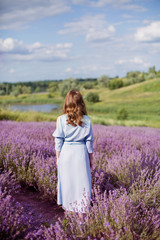 Fototapeta na wymiar Woman in a blue dress at lavender field