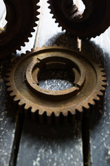 Old rusty gears from machines on a wooden table.