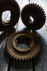 Old rusty gears from machines on a wooden table.