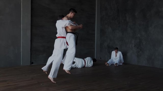 Brave powerful asian guy fighting alone against three strong warriors in white kimono. He perform active martial tricks and makes forceful attack. Slow motion and rapid. Part 1.