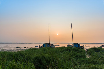 Obraz premium At sunrise on the beach, the masts of the two ships stretched into the sky