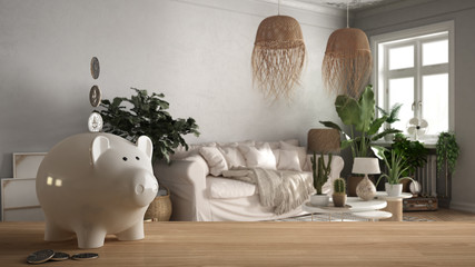 Wooden table top or shelf with white piggy bank with coins, old style living room with sofa and carpet, expensive home interior design, renovation restructuring concept architecture