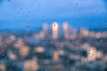 Raindrops on a window pane of glass with blurred background of River Thames and City of London Canary Wharf financial district
