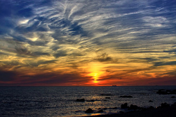 Obraz premium View of the orange sunset on the sea from a rocky beach