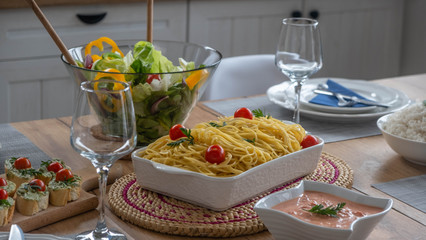 Bolognese with salad, avocado bruschetta and sauce on the table with glasses in background