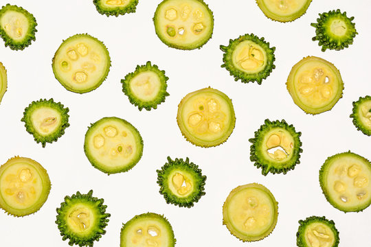 Green colorful spiny gourd and bitter gourd round slices on white background.