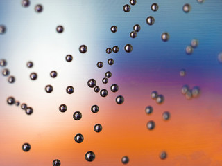 air bubbles on water glass close up with blue orange and purple background