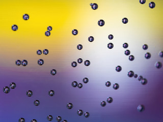 air bubbles on water glass with purple and yellow background 