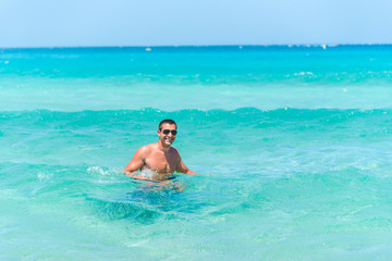 Attractive young caucasian man in the sea , wearing glasses. Summer vacation concept.
