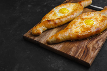 Khachapuri with egg and cheese. Georgian cuisine. On an old wooden background. Free space for text. The view from the top.