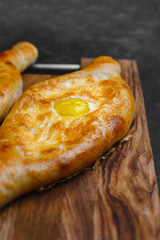 Khachapuri with egg and cheese. Georgian cuisine. On an old wooden background. Free space for text. The view from the top.