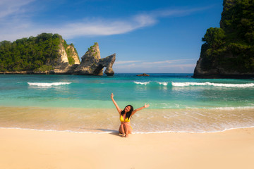 Fototapeta na wymiar outdoors portrait of young happy and beautiful Asian Korean woman in bikini excited having holidays at paradise beach island sitting on the sand by the sea enjoying idyllic travel