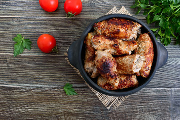 Tasty meat rolls with mushrooms in a ceramic pot on a wooden background. Top view.