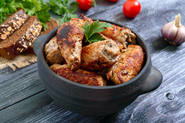 Tasty meat rolls with mushrooms in a ceramic pot on a wooden background