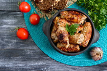 Tasty meat rolls with mushrooms in a ceramic pot on a wooden background. Top view.