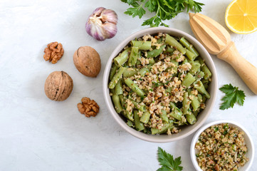 Salad with green beans and spicy walnut sauce in a bowl. Vegetarian, vegan menu. Top view.