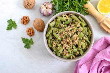 Salad with green beans and spicy walnut sauce in a bowl. Vegetarian, vegan menu. Top view.