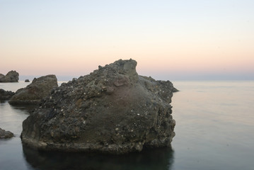 huge stones near a sea coast at the twilight, calm sea bay background