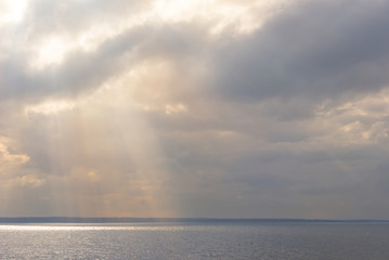 Fototapeta na wymiar sun push through dense clouds above a sea bay