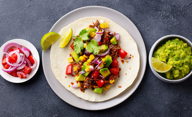 Taco with meat and vegetables. Dark background. Close up. Top view.