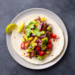 Taco with meat and vegetables. Dark background. Close up. Top view.