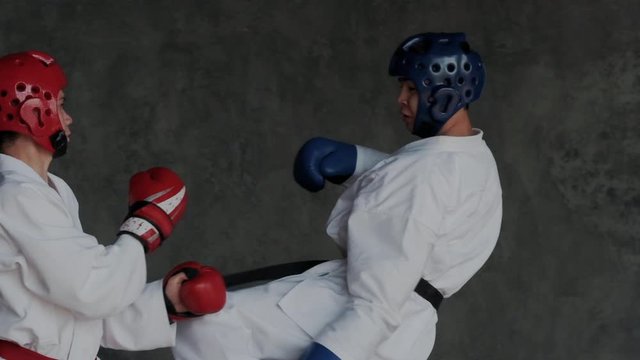 Sparring or single duels in taekwondo class. Pupils kicking in a fighting stance. Forceful attack and defense tactics. Traditional martial arts school. Super slow motion