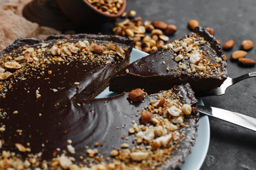 Chocolate cake, chocolate cake, dessert with nuts. a cut piece. Roasted peanuts, almonds and hazelnuts. On dark background. The view from the top. The view from the side. Space for text.