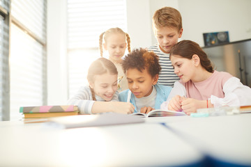 Group of good friends helping twelve-year-old boy with homework task he couldn't do, horizontal shot - obrazy, fototapety, plakaty