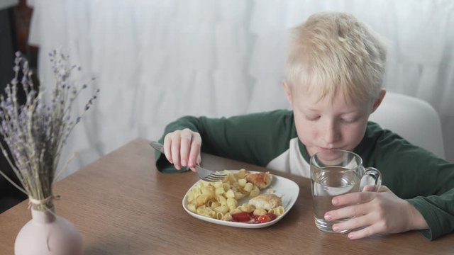 An albino boy eats lunch at home at the table.