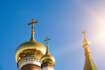 Fototapeta na wymiar Three domes of the Orthodox Church against the blue sky in the sun. Religious architecture