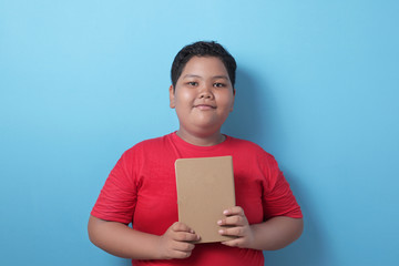 Obraz premium Asian student boy holding book and smile to camera, educational and knowledge concept