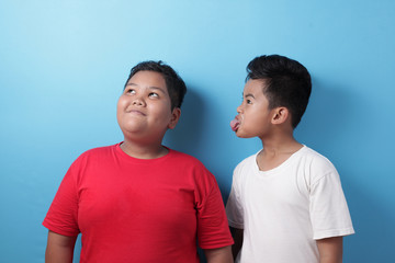 Obraz premium Asian boy bullying mocking other boy, fat boy get bullied at school