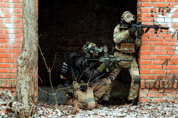 Two men in camouflage cloth green and black uniform with machineguns. Soldiers with muchinegun aims...