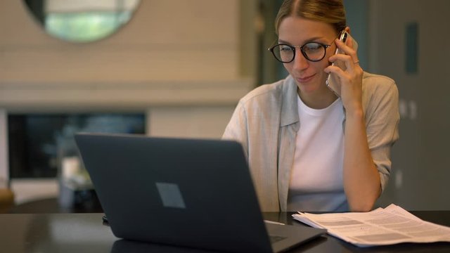 Zoom in on successful female freelancer enjoying cellphone conversation during remote work on modern laptop computer, happy woman communicating with friend while e learning indoors