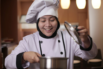 Asian female chef smelling food aroma that she cooked