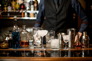 bar counter with a variety of glasses with ice and several bottles with alcoholic drinks