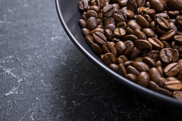 coffee beans in dark bowl cup on isolated dark textured background