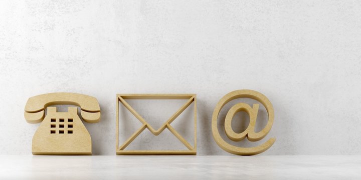 Wooden telephone, envelope letter and e-mail symbols leaning against concrete wall background, contact us symbols or banner
